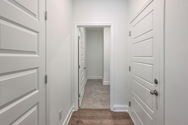 corridor with baseboards and dark wood-type flooring