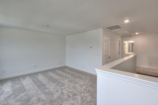 spare room with attic access, visible vents, light carpet, and baseboards