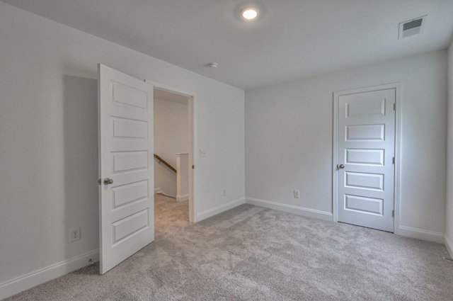 empty room featuring visible vents, light carpet, and baseboards