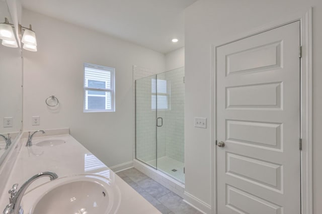 bathroom with double vanity, a stall shower, baseboards, and a sink