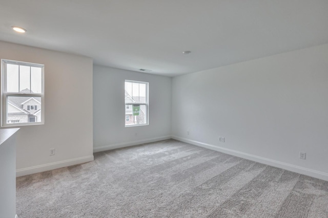 carpeted spare room featuring visible vents and baseboards