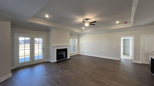 unfurnished living room with a raised ceiling, a fireplace with flush hearth, crown molding, a ceiling fan, and dark wood-type flooring