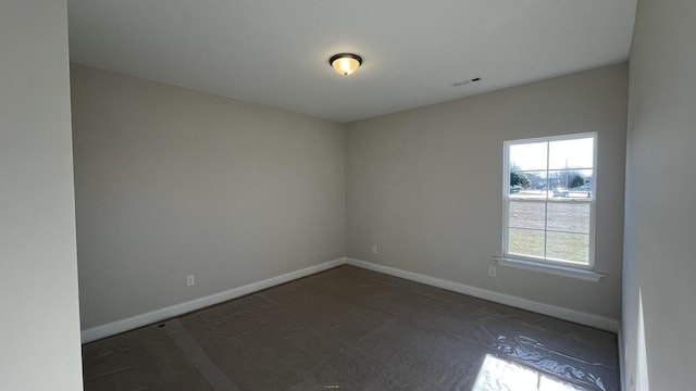 spare room with baseboards and dark colored carpet