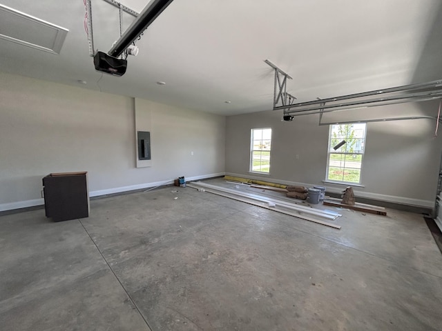 garage with a garage door opener, electric panel, and baseboards