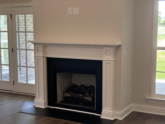 detailed view of a fireplace, wood finished floors, and baseboards