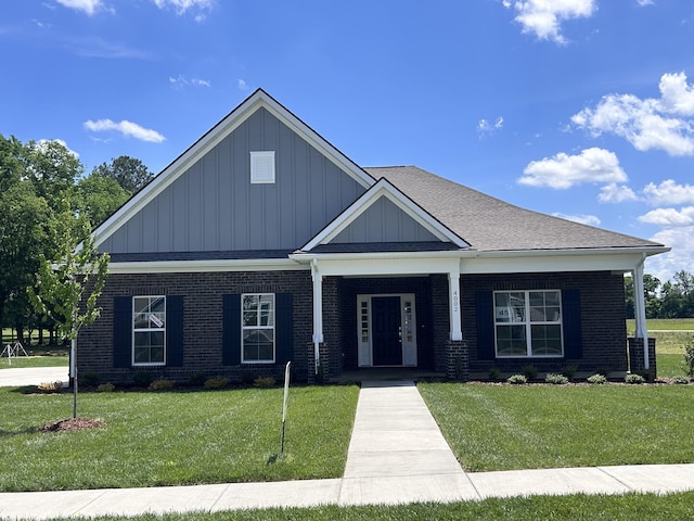 craftsman inspired home with board and batten siding, brick siding, a front yard, and a porch