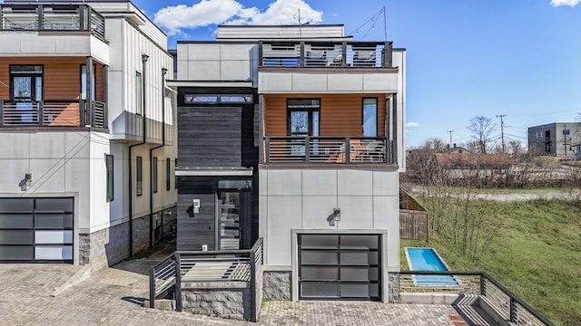 contemporary house with decorative driveway, an attached garage, and a balcony