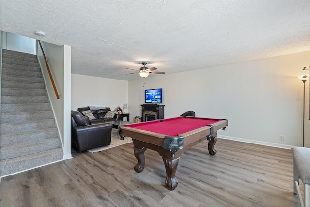 rec room with a textured ceiling, a fireplace, and wood finished floors