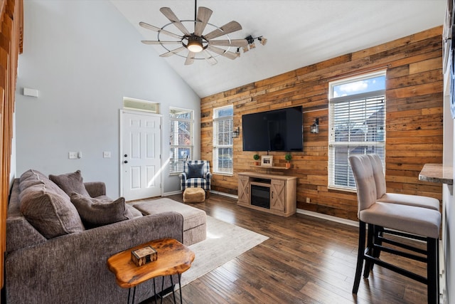 living room featuring a ceiling fan, dark wood finished floors, wood walls, and high vaulted ceiling