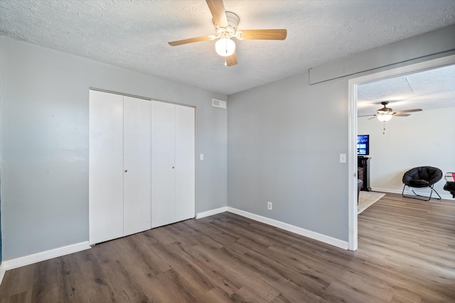 unfurnished bedroom featuring a textured ceiling, baseboards, and wood finished floors