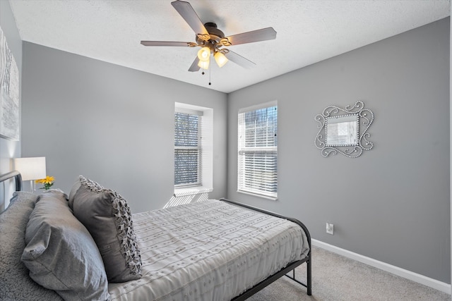 carpeted bedroom with ceiling fan, baseboards, and a textured ceiling