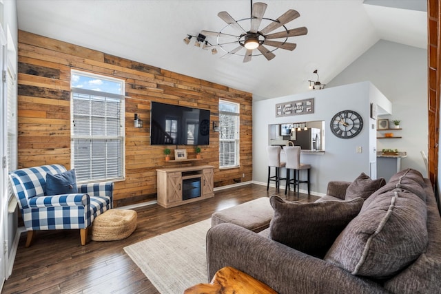 living room with wood walls, ceiling fan, wood finished floors, and a glass covered fireplace