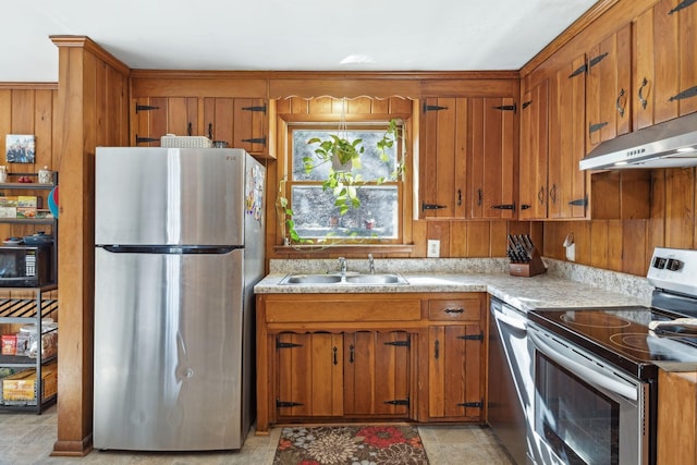 kitchen featuring brown cabinetry, appliances with stainless steel finishes, light countertops, under cabinet range hood, and a sink