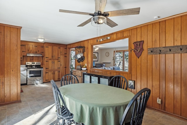 dining room with wooden walls, baseboards, and a ceiling fan