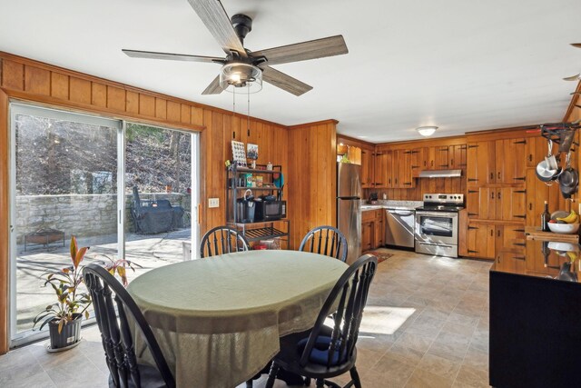 dining space with wooden walls and a ceiling fan