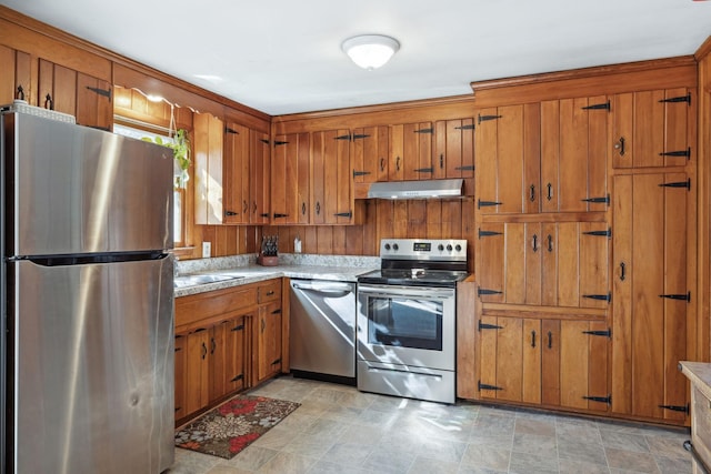 kitchen with brown cabinets, under cabinet range hood, stainless steel appliances, and light countertops