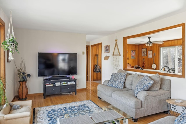 living area featuring ceiling fan, baseboards, and wood finished floors