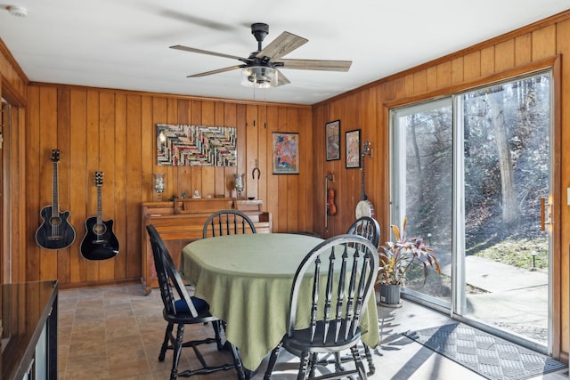 dining room with a healthy amount of sunlight, wood walls, and ceiling fan