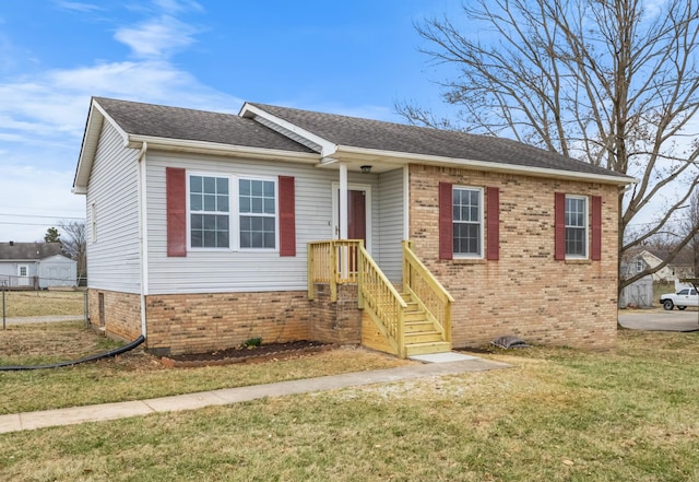 view of front of home featuring a shingled roof, a front yard, brick siding, and fence