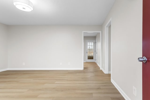 empty room featuring light wood finished floors and baseboards