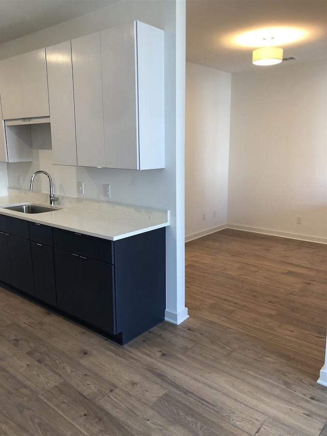 kitchen with baseboards, dark wood finished floors, modern cabinets, light countertops, and a sink