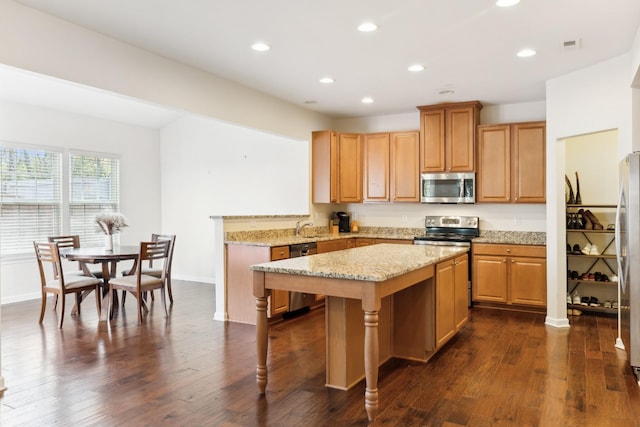 kitchen featuring a sink, stainless steel appliances, a kitchen island, and dark wood finished floors