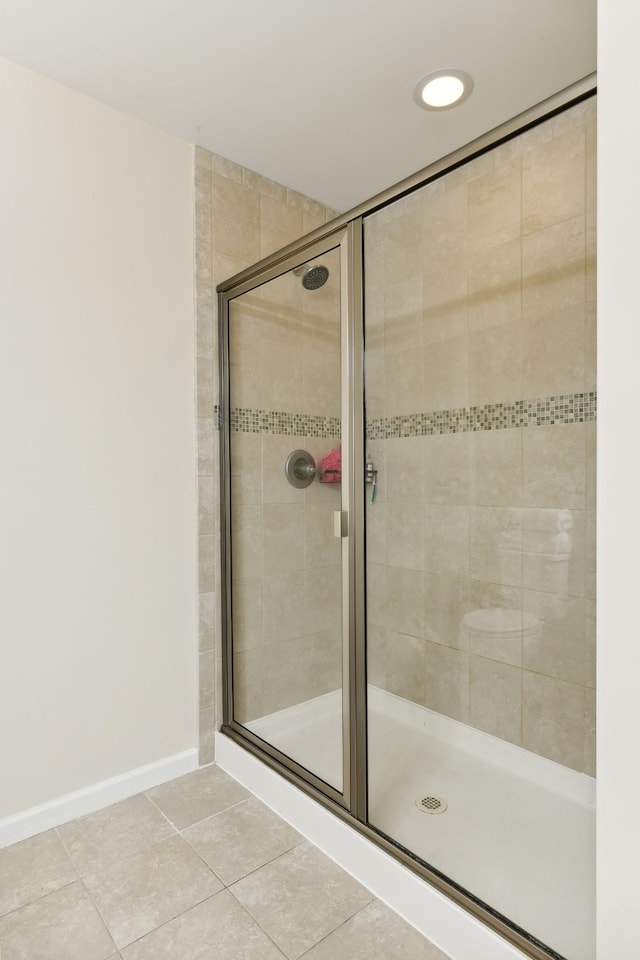 full bath with tile patterned flooring, a shower stall, and baseboards