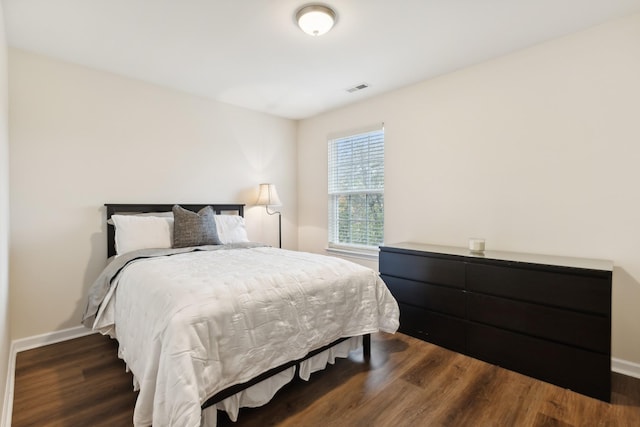 bedroom with visible vents, baseboards, and wood finished floors