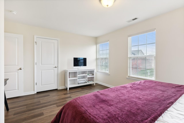 bedroom with wood finished floors, visible vents, and baseboards