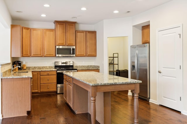 kitchen with light stone countertops, recessed lighting, appliances with stainless steel finishes, a center island, and dark wood-style floors