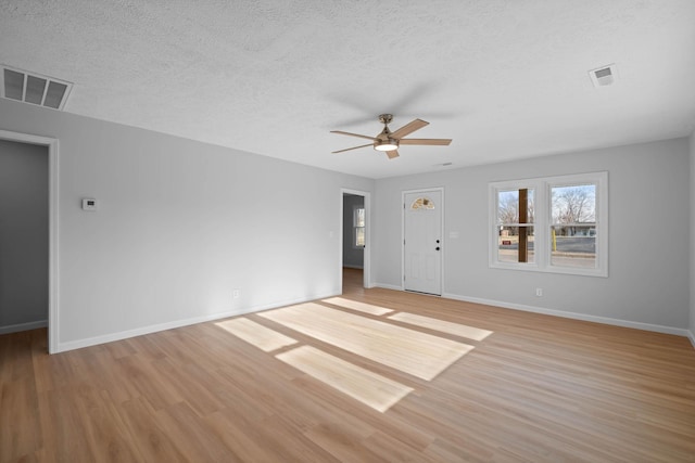 unfurnished living room featuring light wood-style floors, baseboards, visible vents, and a textured ceiling