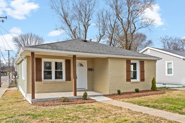 bungalow with covered porch, brick siding, roof with shingles, and a front yard