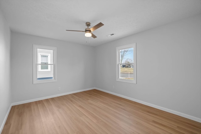 empty room with visible vents, baseboards, a ceiling fan, a textured ceiling, and light wood-type flooring