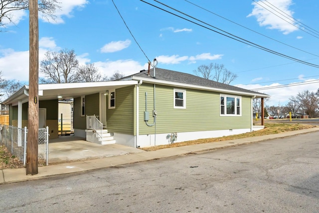 view of front facade featuring a carport, a shingled roof, crawl space, and fence