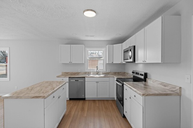 kitchen with stainless steel appliances, light wood-style flooring, a sink, and light countertops