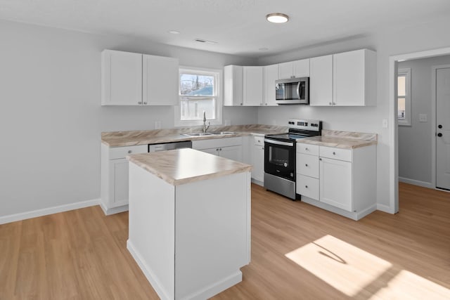 kitchen featuring stainless steel appliances, light countertops, a sink, and light wood-style flooring