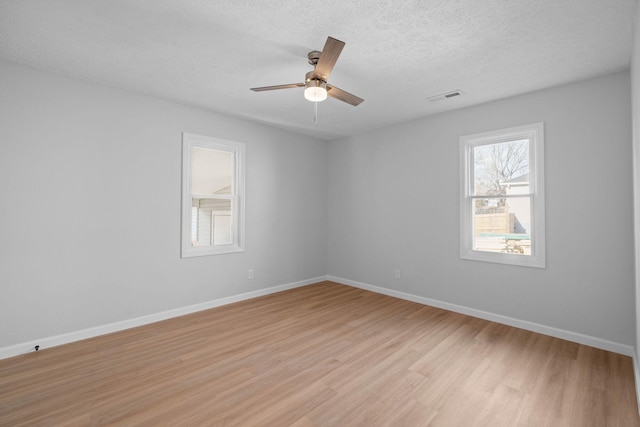 unfurnished room featuring baseboards, visible vents, ceiling fan, a textured ceiling, and light wood-type flooring