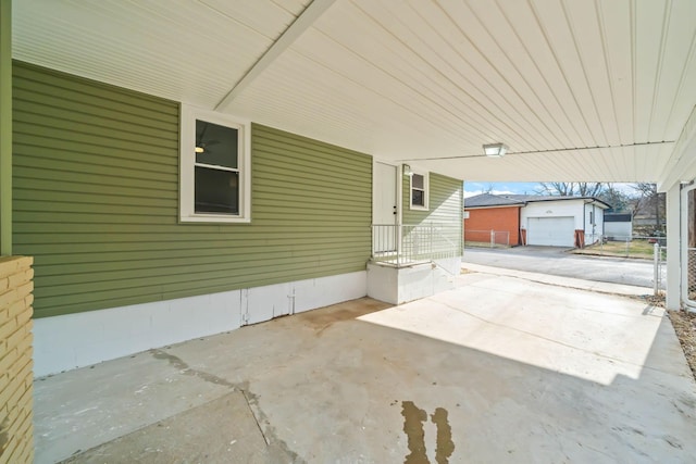 view of patio with driveway, an outdoor structure, and fence