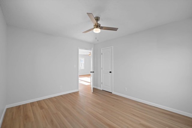 spare room with ceiling fan, light wood-style flooring, and baseboards