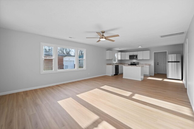 unfurnished living room featuring light wood-type flooring, visible vents, ceiling fan, and baseboards