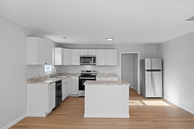 kitchen featuring white cabinets, appliances with stainless steel finishes, light countertops, and a sink