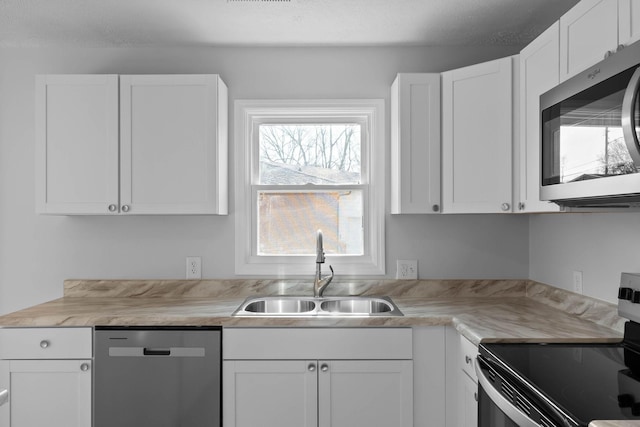 kitchen featuring stainless steel appliances, a sink, light countertops, and white cabinetry