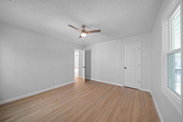 unfurnished room with light wood-type flooring, plenty of natural light, and baseboards