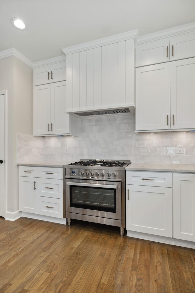 kitchen with wood finished floors, light countertops, wall chimney range hood, stainless steel range, and crown molding