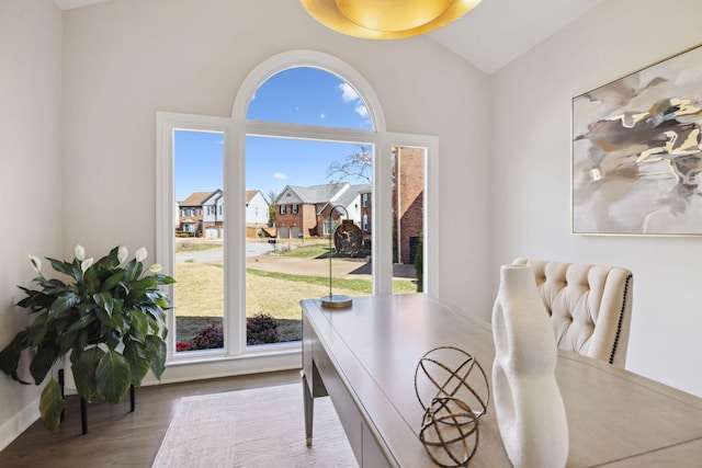 home office featuring a residential view, vaulted ceiling, and wood finished floors