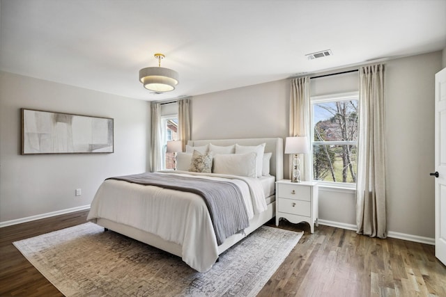 bedroom with visible vents, baseboards, and wood finished floors