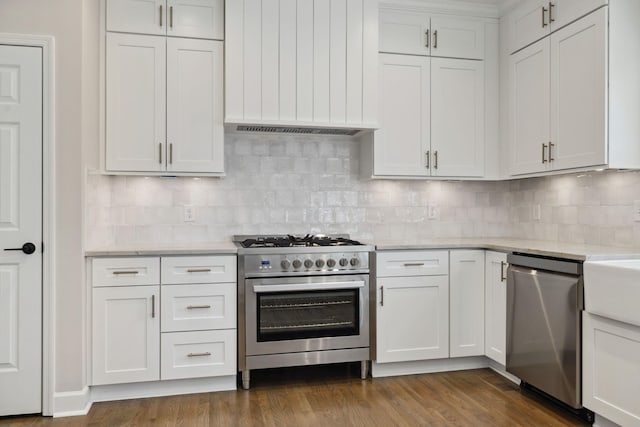 kitchen featuring stainless steel appliances, tasteful backsplash, dark wood-type flooring, and white cabinetry