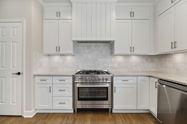 kitchen featuring appliances with stainless steel finishes, dark wood-style flooring, premium range hood, and white cabinetry