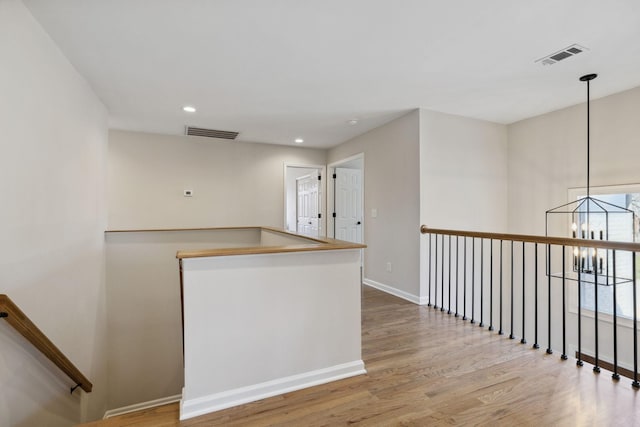 interior space with baseboards, visible vents, a chandelier, and wood finished floors