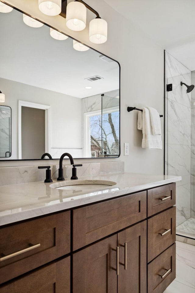 full bath with marble finish floor, a marble finish shower, visible vents, and vanity